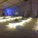 A large tent with specialty lighting, tables, and chairs for a unique event setting.