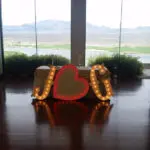 A wedding reception with a heart shaped table adorned with marquee letter rentals in front of a large window.