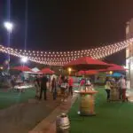 An open field with cocktail tables and red umbrellas