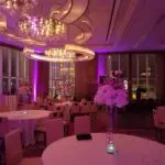 A stunning ballroom adorned with vibrant purple lighting, featuring elegantly arranged tables for any memorable event.