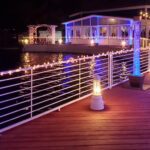 A deck with LED blue lights on it next to a body of water.