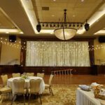 A banquet room set up with tables, chairs, and curtain walls.