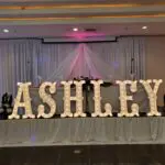 The name Ashley is illuminated on a table with a Marquee Letter rental.