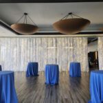 A room with blue tablecloths and curtain lights.