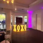 A room with purple lights and a sign that says xoxo, available for marquee letter rental.