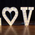 An outdoor wedding ceremony setup with LOVE marquee letters