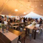 An indoor event with wooden tables and white table covers