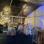 An indoor event setup with white tables and chairs