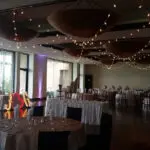 An indoor event with white tables and black chairs