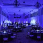 A large ballroom in Las Vegas with blue lighting and tables available for Uplight Rentals.