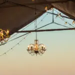 Chandeliers hanging from the ceiling of a tent at a Chandelier & Lamp Post Rental Las Vegas event.