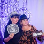 Two women wearing adorable hats and holding statement cards for photobooth