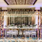 A wedding reception set up with white chairs and curtain light walls.