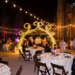 A wedding reception with tables and chairs adorned with specialty string lights.