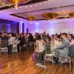 An indoor event setup with lots of people sitting on their chairs