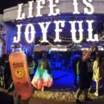 A person holding up a sign that says life is joyful, illuminated by SPECIALTY lighting.