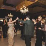 A bride and groom gracefully dancing under the romantic glow of bistro lighting at their enchanting wedding reception.