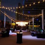 A large outdoor area with tables and chairs lit up with string lights at the Las Vegas strip.