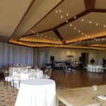 A banquet room with tables and chairs, adorned with beautiful string lights, perfect for Event Lighting at Red Rock Country Club Las Vegas.