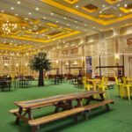 A large ballroom with yellow tables and chairs featuring event lighting at the Las Vegas strip.