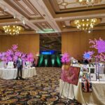 A large ballroom filled with event lighting, tables, and chairs.