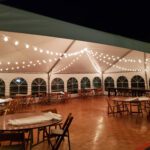 An event tent with tables and chairs adorned with beautiful string lights.