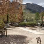 An outdoor area with tables and chairs in front of a mountain, enhanced with event lighting.