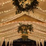 A tent covered in fairy lights at a wedding with event lighting.