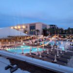 A rooftop pool and lounge area at dusk, adorned with mesmerizing event lighting, overlooking the vibrant Las Vegas strip.