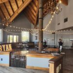 A large room adorned with wooden beams and tastefully decorated with string lights, providing a warm and rustic atmosphere perfect for events.