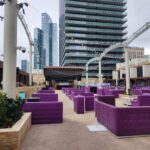 A large outdoor area with purple couches and chairs, set against the dazzling event lighting of the Las Vegas strip.