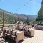 A stunning wedding reception set up on a deck overlooking the majestic mountains of Mt Charleston, Las Vegas. The event is beautifully illuminated with expertly designed event lighting, creating an enchanting atmosphere.