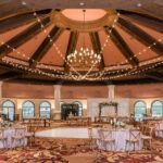 An elegant wedding reception in a large ballroom with breathtaking chandeliers, complemented by exquisite event lighting at JW Marriott Las Vegas.