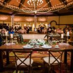 A wedding reception with tables and chairs in the middle of the room, enhanced by event lighting at JW Marriott Las Vegas.