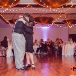 A couple hugging on the dance floor at a wedding reception, illuminated by elegant event lighting.