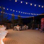 A wedding reception with string lights on a deck, featuring stunning lighting that creates a romantic ambiance.