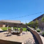 A backyard with a fire pit and patio furniture featuring Long-Term Lighting Solutions for outdoor Lights in Las Vegas.