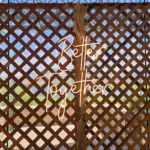 A wooden fence with a LED Flex Neon sign that says "better together.