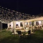 A wedding reception under enchanting string lights in a charming grassy area, enhanced by delicate Curtain Light Walls.