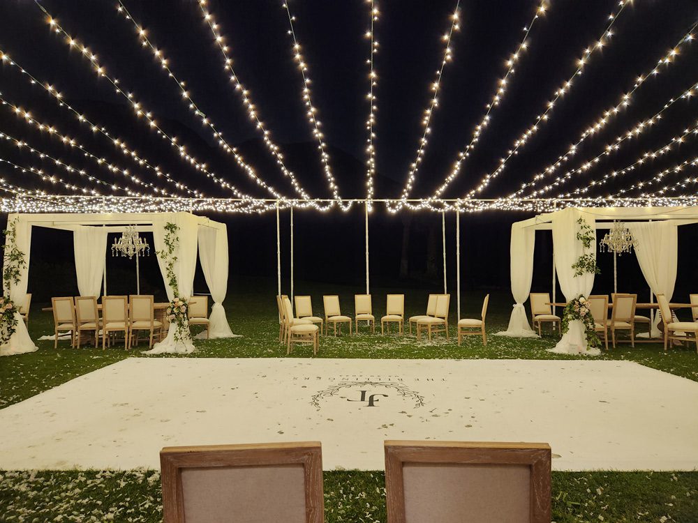 A wedding reception with a white floor on top of the grass with JF initials