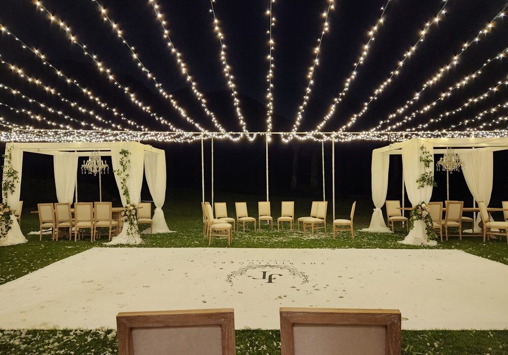 A wedding reception with a white floor on top of the grass with JF initials